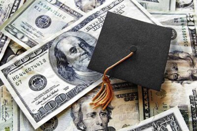 graduation cap on dollar bills