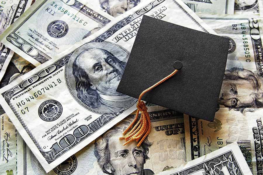 graduation cap on dollar bills